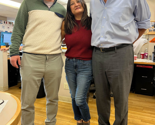 3 staff members smiling during the International Food Day lunch.