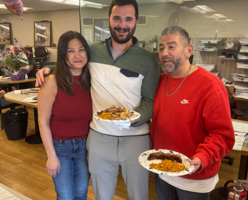 3 staff members holding food during the International Food Day lunch.