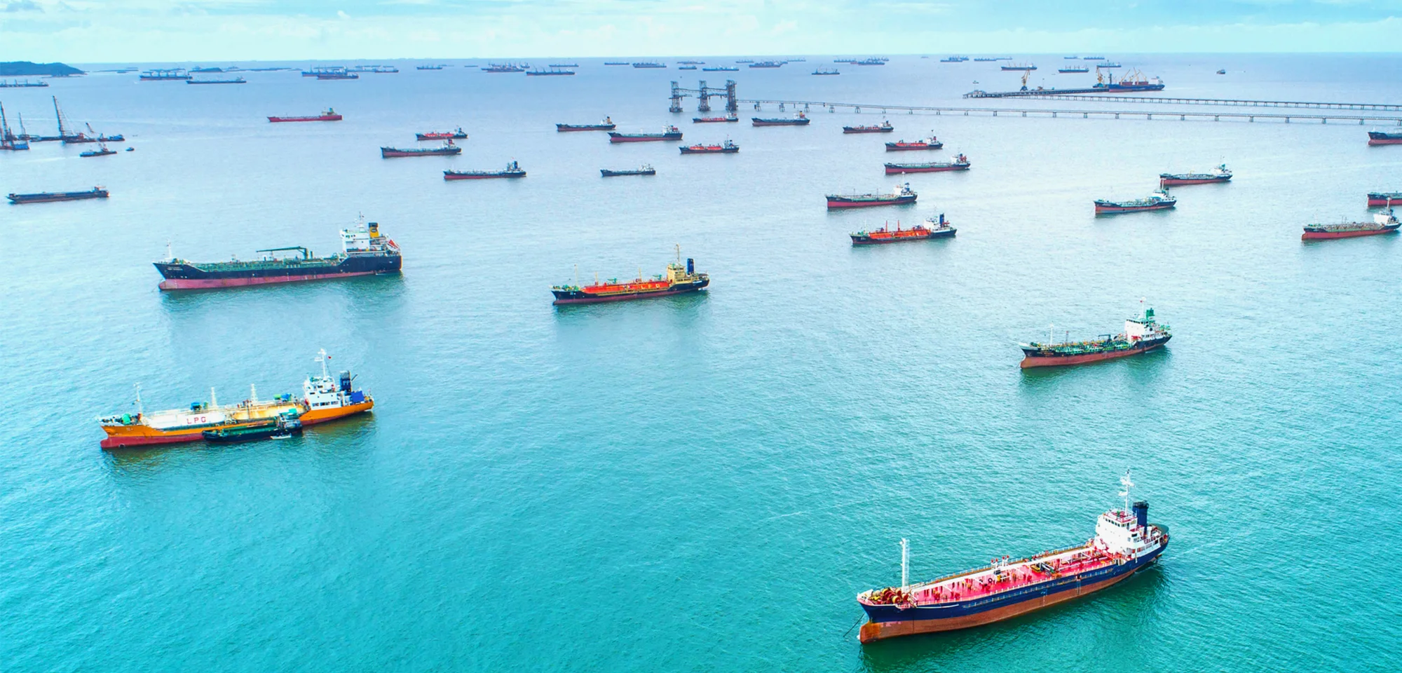 Multiple cargo ships in the clear-blue ocean.